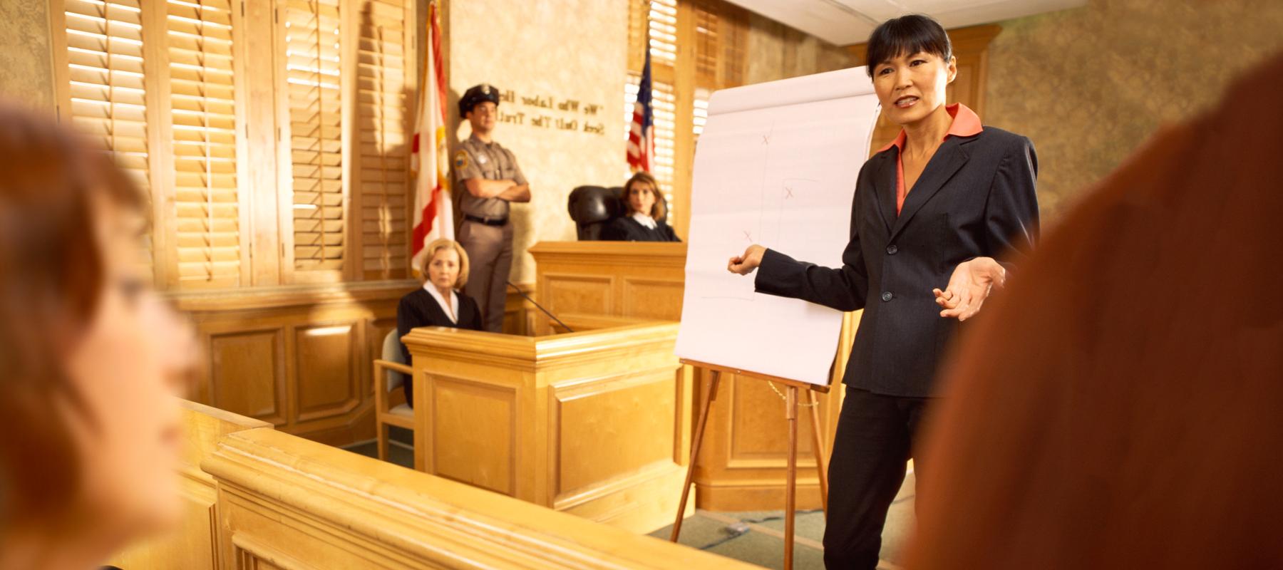 female in a suit talks to a jury in a court room