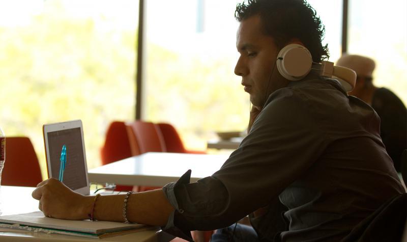 student with headphones at a laptop studying