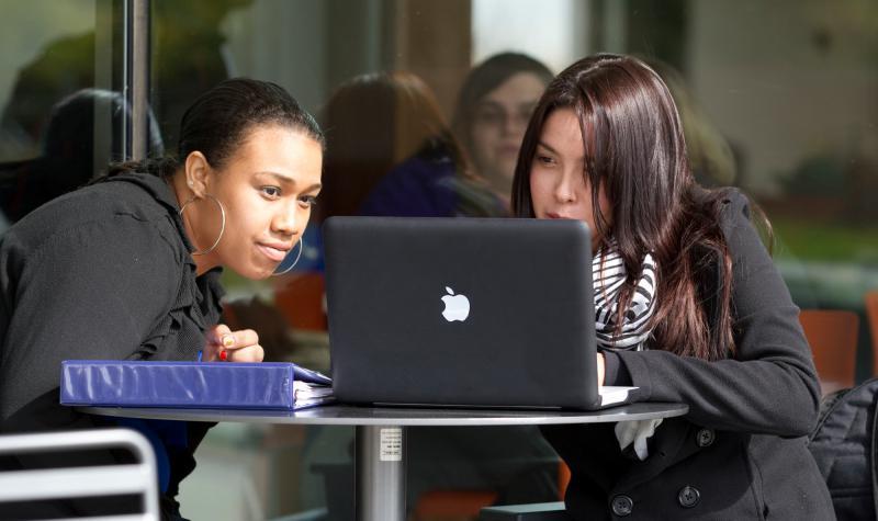 two female students work together on a computer.
